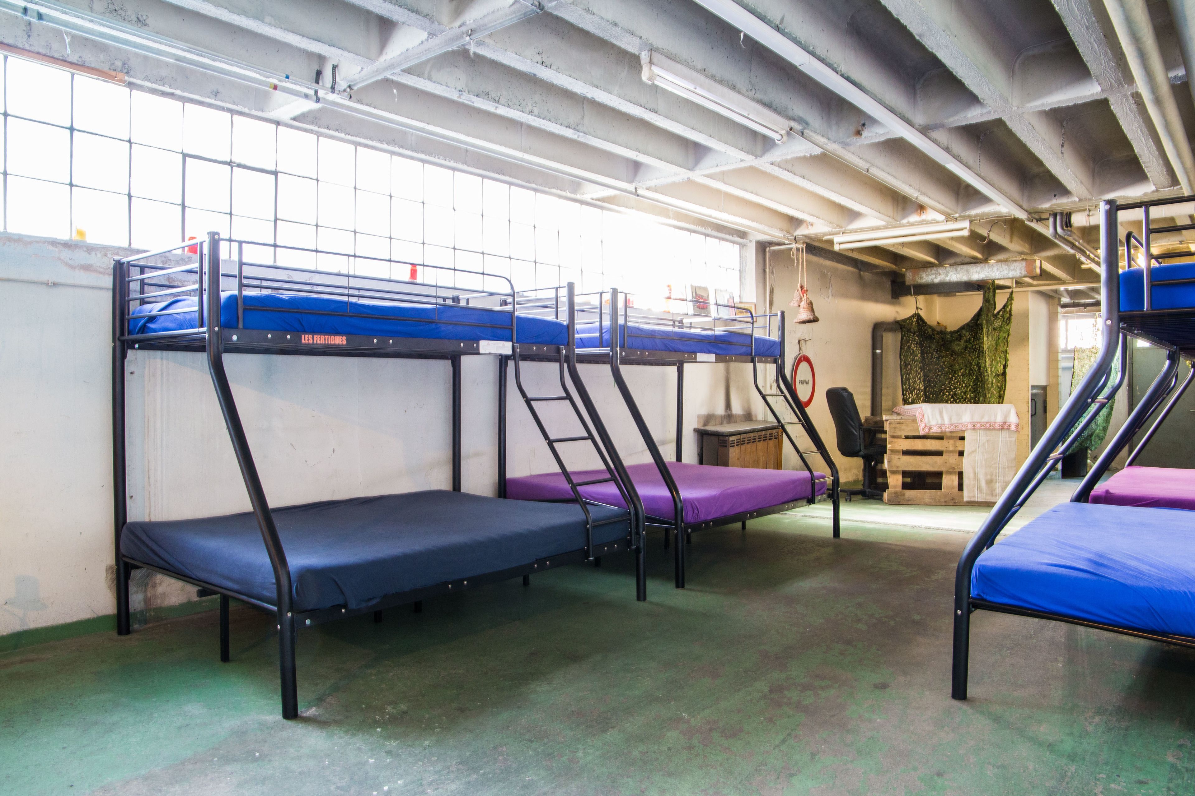 Bunk beds in a dormitory room with a window and a door to the right.