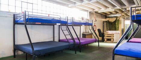 Bunk beds in a dormitory room with a window and a door to the right.