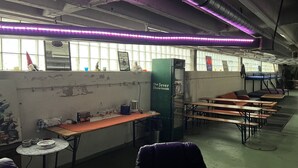 A room with tables and benches, a vending machine, and a window with artwork. - Boot Camp Central - Hostel (Friedrichshafen)