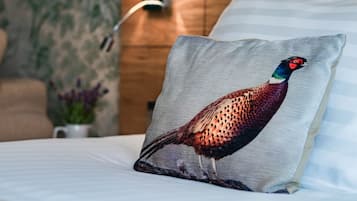 A pillow with a peacock design on a bed with striped pillows.
