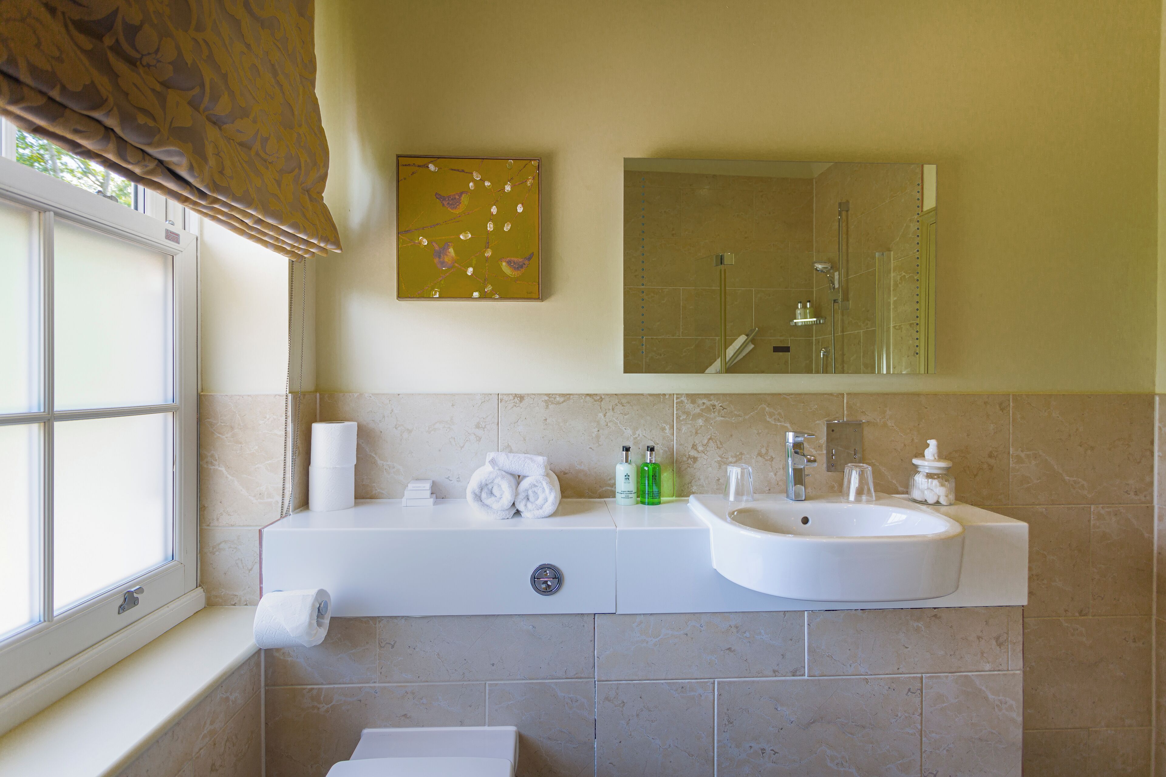 A bathroom with a window, a sink, a mirror, and a towel rack.