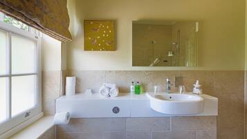 A bathroom with a window, a sink, a mirror, and a towel rack.