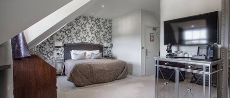 A bedroom with a bed, a dresser, a television, and a desk.