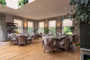 A spacious dining area with wicker furniture and large windows. - The Pheasant Hotel, Holt, Norfolk (Holt)