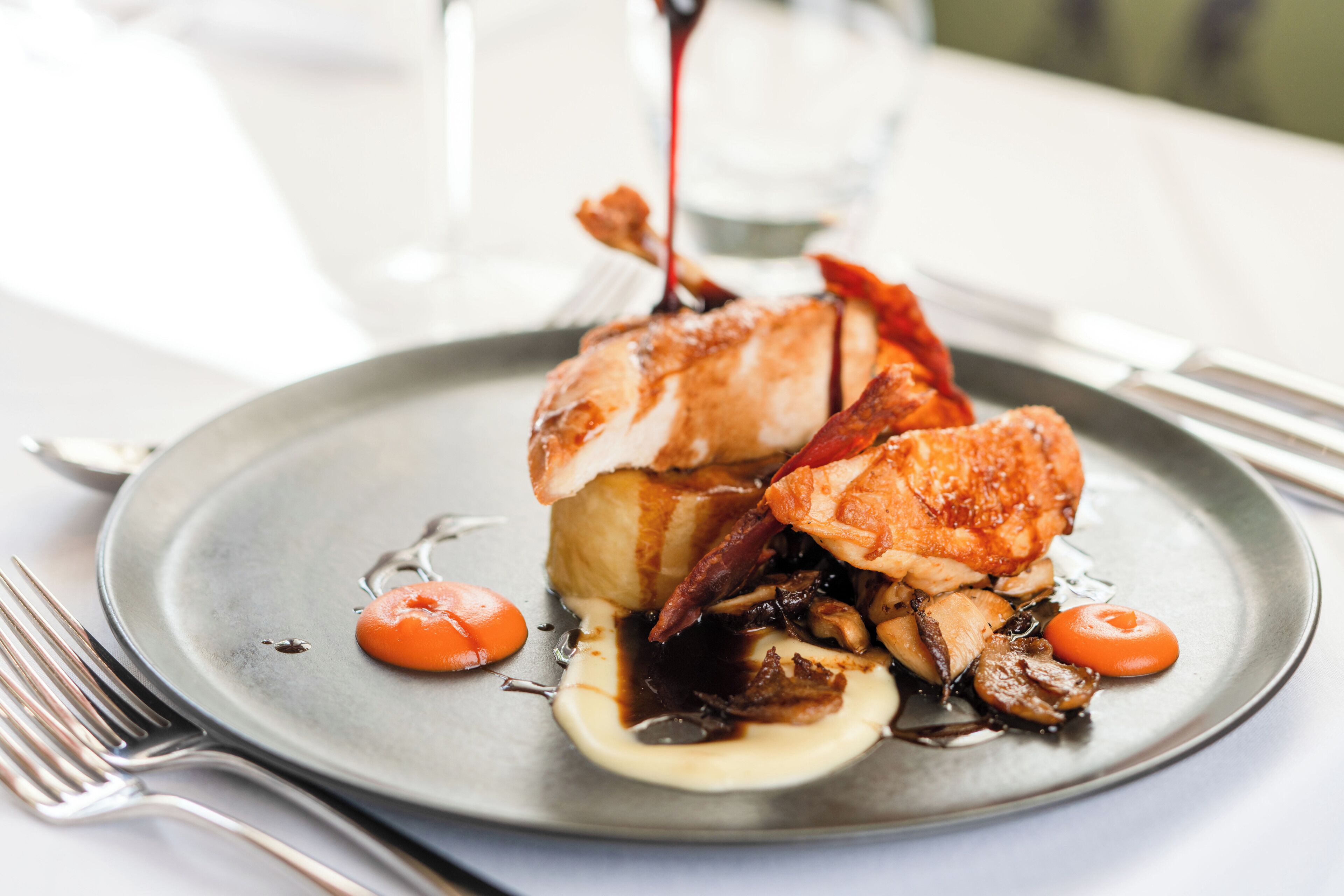 A plate of food with a sauce being poured over it.
