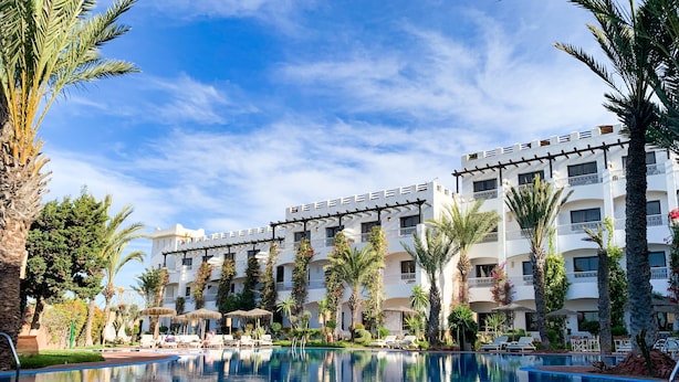 Una piscina al aire libre, sombrillas, sillones reclinables de piscina