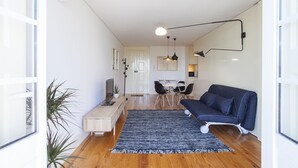 A modern living room with a sofa, a coffee table, and a dining area with chairs and a table. - Liiiving In Porto - Central Secret Balcony (Porto)