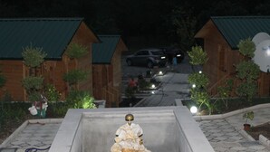 A wooden cabin with a green roof, a paved driveway, and a statue of a rabbit.