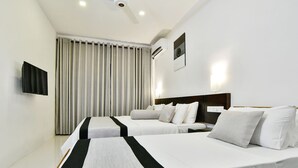 A hotel room with two beds, a flat-screen TV, an air conditioning unit, and a large window with curtains.