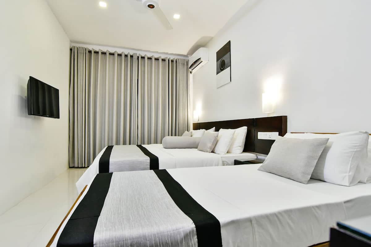 A hotel room with two beds, a flat-screen TV, an air conditioning unit, and a large window with curtains.