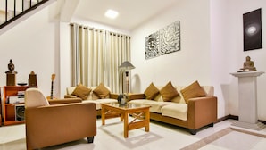 A living room with a sofa set, a coffee table, a lamp, and a Buddha statue.