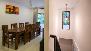 A dining area with a wooden table and chairs, a ceiling fan, and a window with a view of greenery.