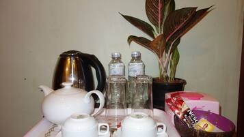 Une table avec une théière, des tasses, des bouteilles, une plante et une boîte de café instantané Nescafé.