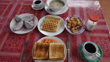 A table with a meal consisting of toast, soup, a bowl of fruit, and a cup of coffee.
