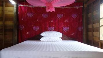 Una cama con sábanas blancas, dosel rosa y pared roja con motivos de corazones.
