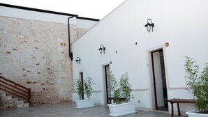 Un patio con pared de ladrillo, paredes blancas y plantas en macetas.