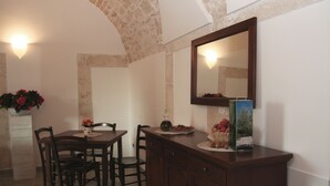 Un comedor con una mesa y sillas de madera, un armario con espejo y un jarrón con flores.