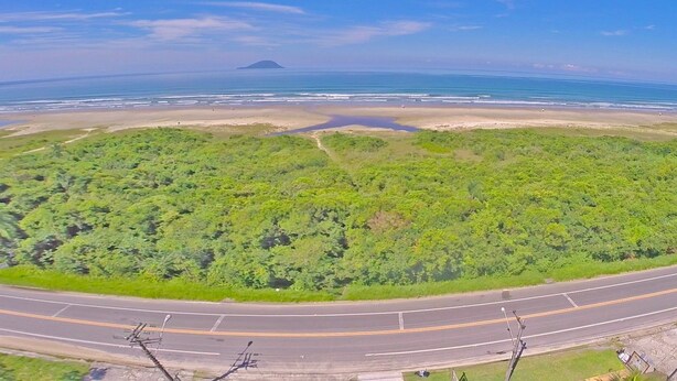 Vue aérienne d’une route côtière bordée d’une plage et d’une végétation luxuriante.