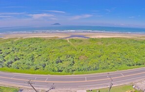 Vue aérienne d’une route côtière bordée d’une plage et d’une végétation luxuriante.
