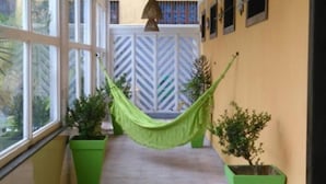 Un couloir agrémenté d’un hamac, de jardinières vertes et d’un mur orné d’un motif en chevrons.