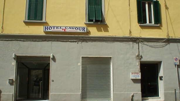 En byggnad med en skylt ovanför ingången där det står ”HOTEL CAVOUR”.