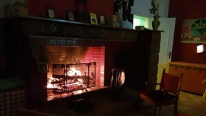 Ein gemütliches Zimmer mit Kamin, einem Sessel und einem Tisch.