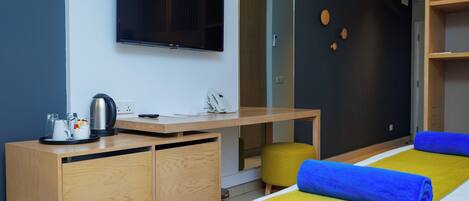 Una habitación de hotel con cama, escritorio, televisor y un pequeño rincón de descanso.