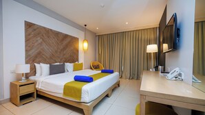 A hotel room with a bed, bedside table, lamp, chair, desk, and a telephone.