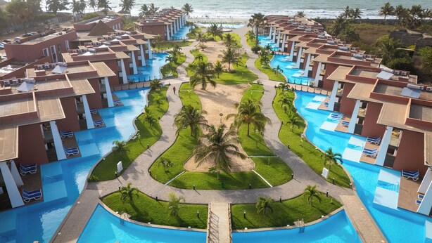 A resort with multiple swimming pools, palm trees, and a beach view.