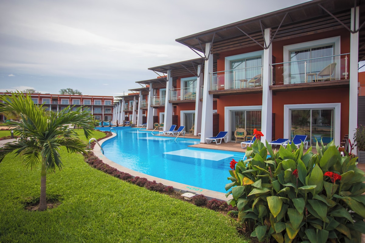 A hotel with a swimming pool, multiple balconies, and outdoor seating areas.