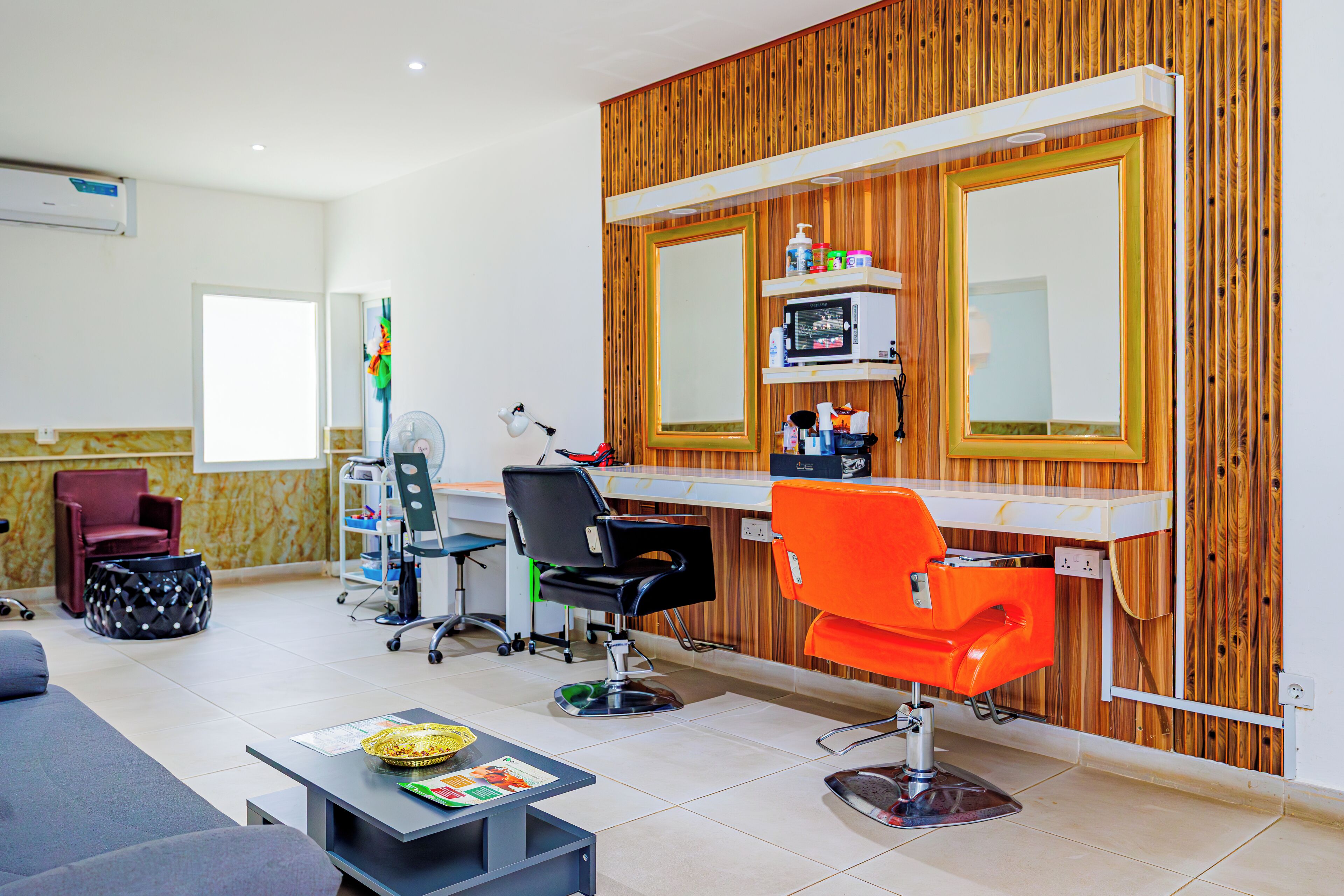 A salon with a wooden wall, a mirror, and two hairdressing chairs.
