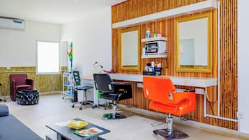A salon with a wooden wall, a mirror, and two hairdressing chairs.