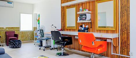 A salon with a wooden wall, a mirror, and two hairdressing chairs.