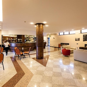 Un vestíbulo con zona de bar, asientos y una columna central.