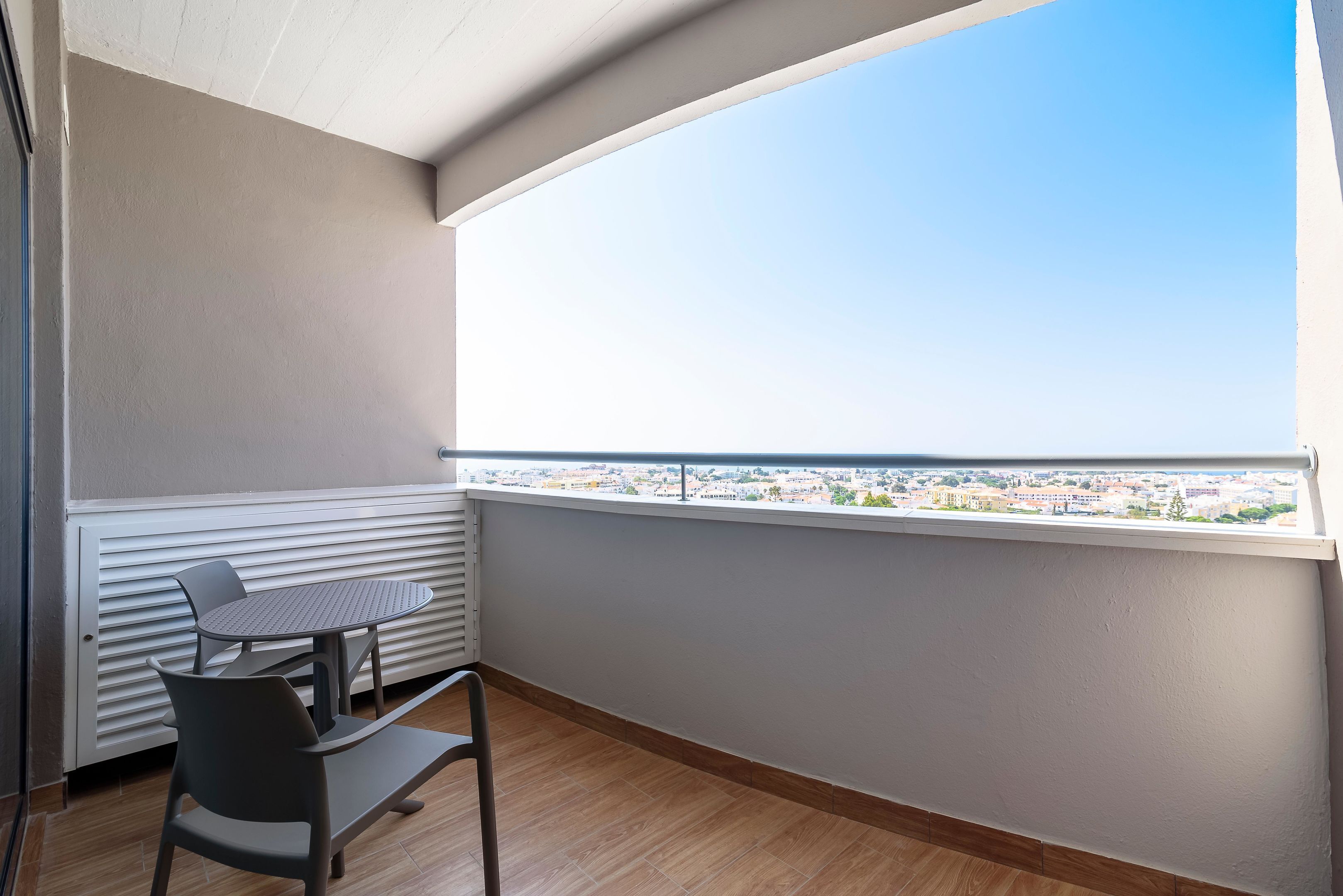 Un balcon avec une table et des chaises, un radiateur et une vue sur la ville.