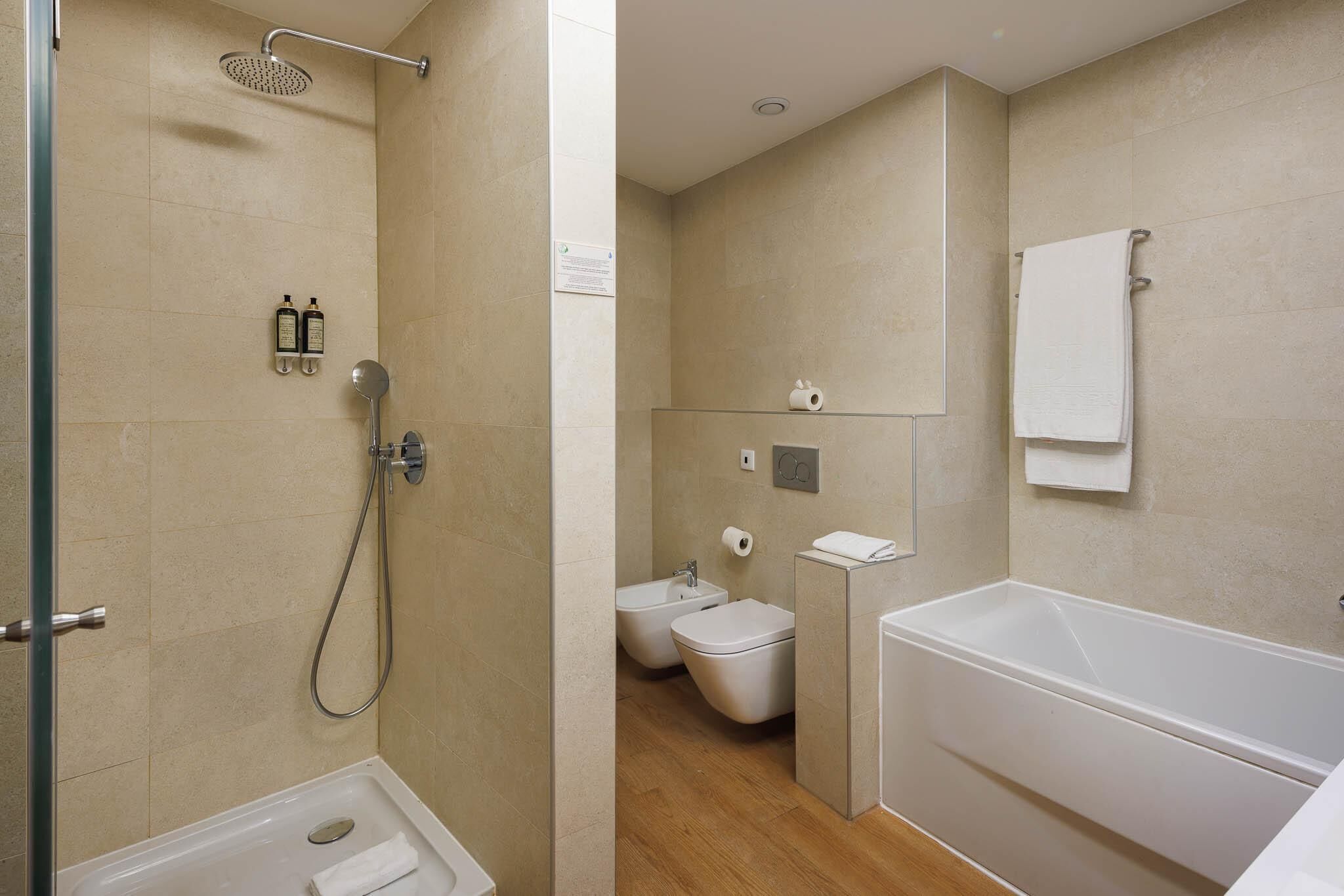 A modern bathroom with a shower, toilet, bidet, and bathtub.