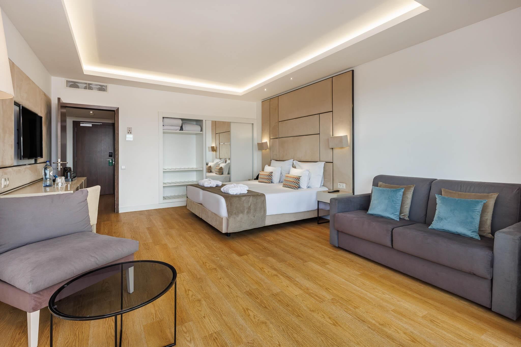 Una habitación de hotel moderna con cama, sofá, televisión y escritorio.