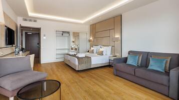 Una habitación de hotel moderna con cama, sofá, televisión y escritorio.
