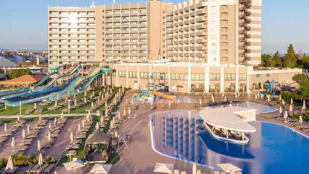 A resort with a large pool, multiple water slides, and numerous sun loungers.