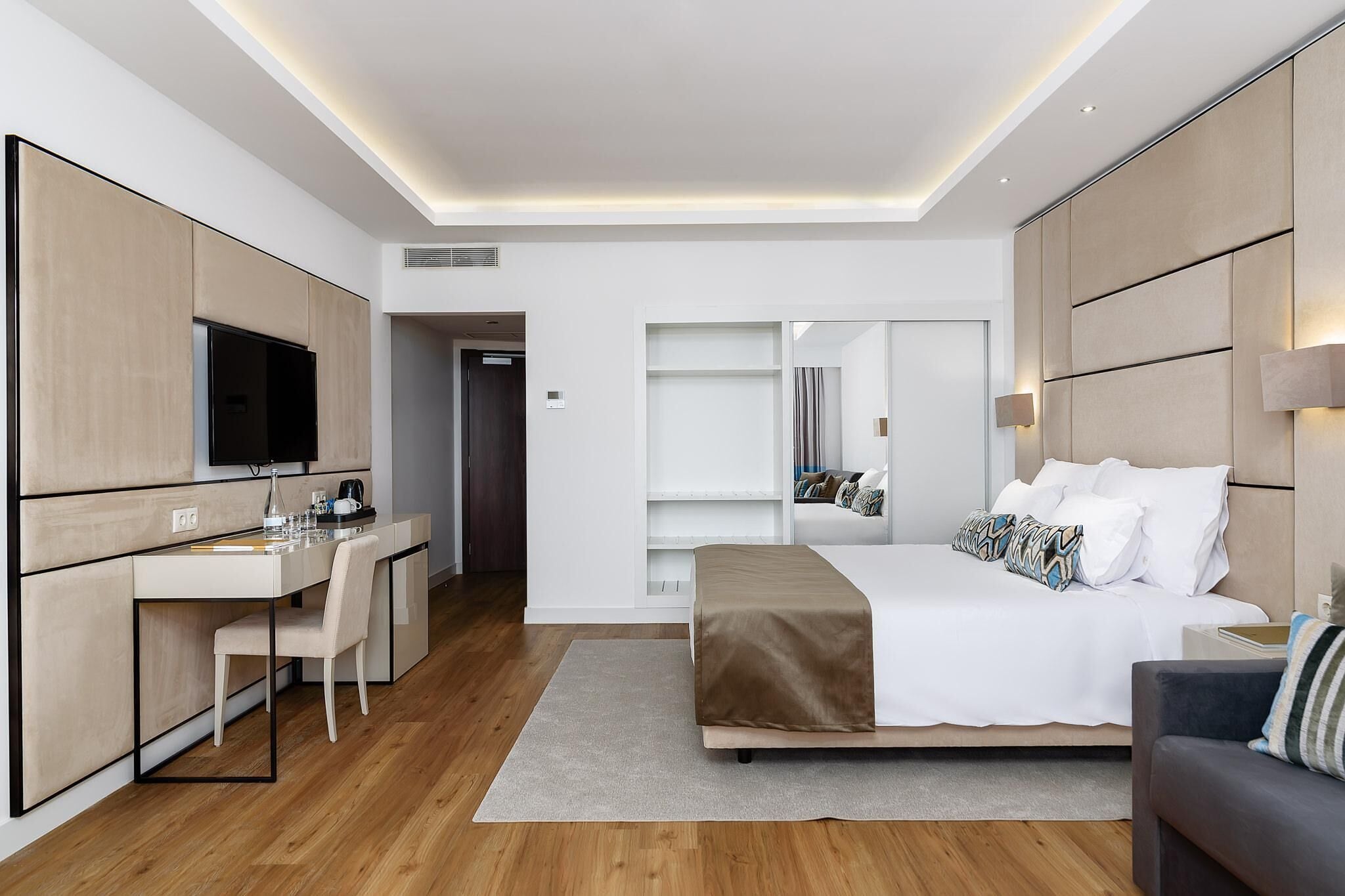 A modern hotel room with a bed, a desk, and a television.