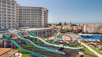 A resort with multiple swimming pools, a large water park with slides, and a view of the sea.