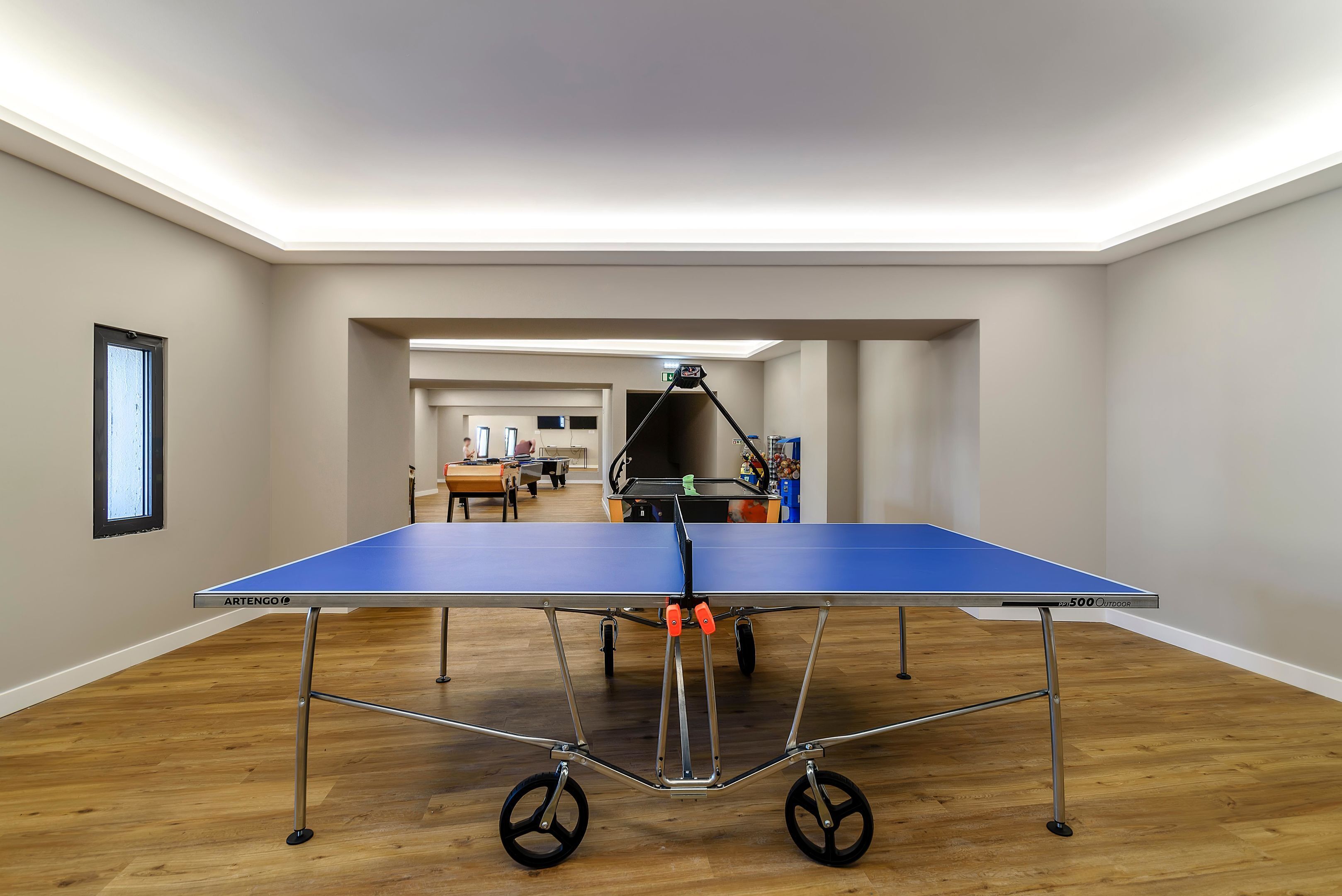 A ping pong table in a room with wooden flooring and white walls.