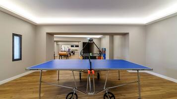 A ping pong table in a room with wooden flooring and white walls.