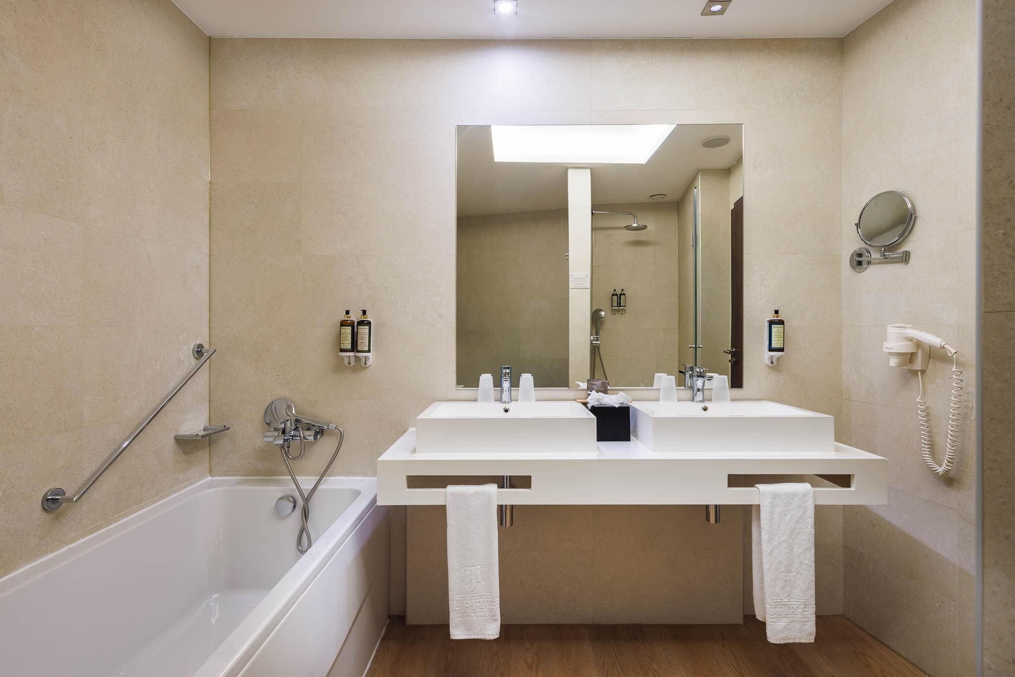 Ein modernes Badezimmer mit Waschbecken, Badewanne, Dusche und Spiegel.