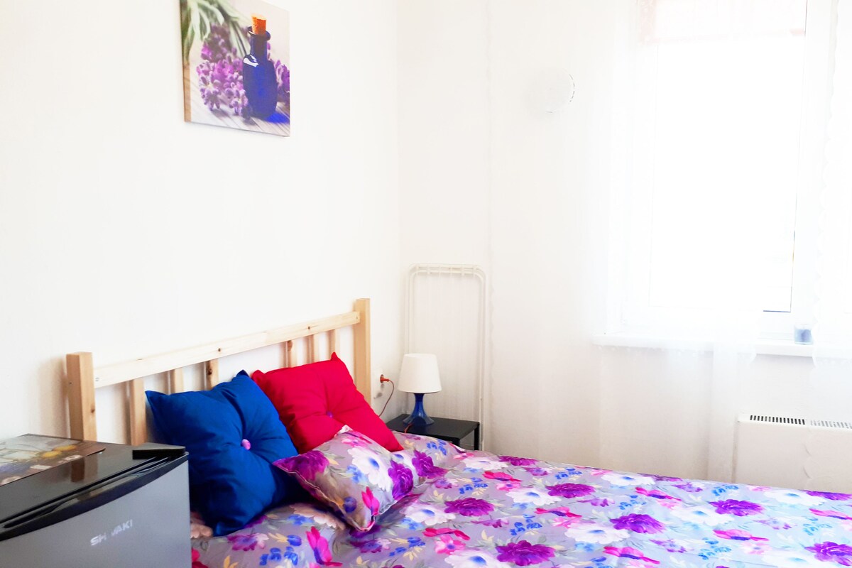 A bed with a floral bedspread, a wooden headboard, and two pillows.