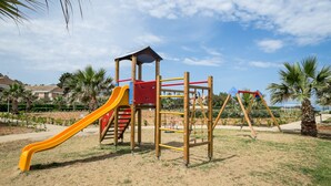 Un parque infantil con tobogán, estructuras para escalar y columpios.