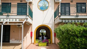 Un edificio con un arco central, un mural con la palabra "Agave" y plantas en macetas en la entrada.