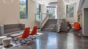 A modern hotel lobby with a staircase, seating areas, and large windows. - Dorma Liberdade (Lisbon)