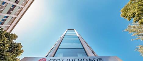 A modern building with a glass facade and the sign "exe LIBERDADE" at the base.