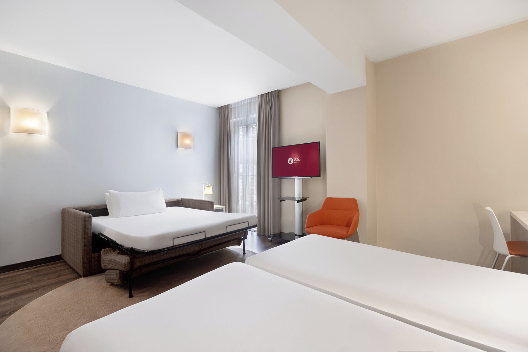 Une chambre d’hôtel avec deux lits, un téléviseur à écran plat, un bureau et une chaise.